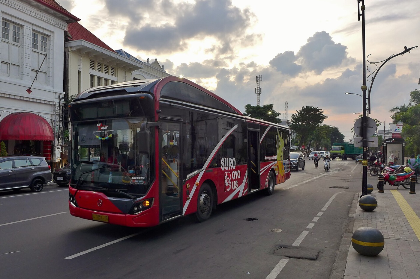 Bus Suroboyo berhenti di halte, dengan penumpang yang menunggu di pinggir Jalan Rajawali.