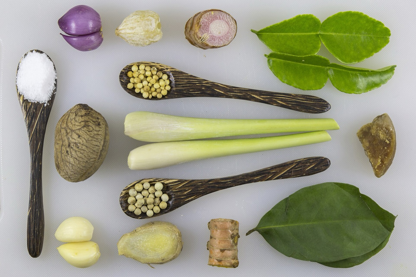 Sepiring rawon panas dengan tauge, daun bawang, dan kerupuk di atas meja kayu.